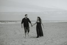 a man and woman holding hands while walking on the beach