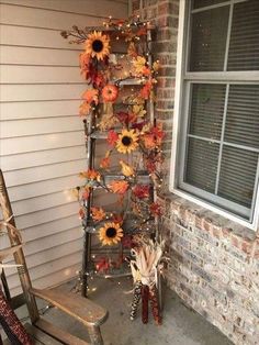 an old ladder decorated with sunflowers and fall leaves is sitting outside the house