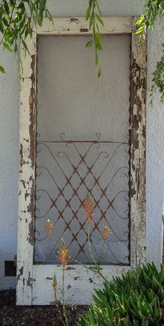 an old window frame with vines growing out of it and some flowers in the foreground