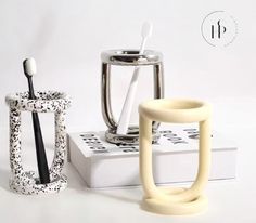 two toothbrush holders sitting next to each other on top of a white box with black and white designs