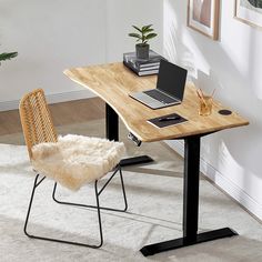 a laptop computer sitting on top of a wooden desk next to a chair and potted plant