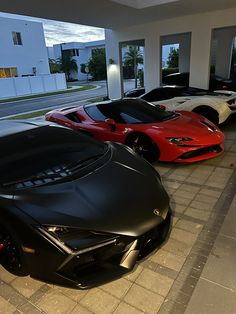 three different colored sports cars are parked in a row on the side of a building