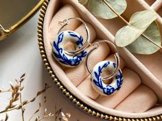 The perfect earrings for pottery lovers, or as a traditional pottery gift to celebrate a 9th wedding anniversary! Classic Blue Willow charm meets modern flair, with our beautifully chic hoop earrings, adorned with hand-painted ceramic donuts in serene shades of blue and white.  Designed to add a touch of sophistication to your outfit, each ceramic donut is meticulously hand-painted, making every pair a work of art. With a contemporary hoop design, these earrings are versatile and perfect for any occasion, whether you're dressing up for a special event or adding a pop of color to your everyday look. Material: 925 Sterling silver or gold plated silver Dimensions: Earring Hoop: 18mm x 20mm; Ceramic Hoop: 18mm approx. Earrings are lovingly handmade in our Chester studio, and presented in brand Ceramic Donut, 9th Wedding Anniversary, Chinoiserie Pattern, Earrings Gold Hoop, Earring Hoop, Traditional Pottery, Porcelain Earrings, Ceramic Earrings, Pottery Gifts