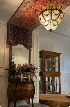 an ornately decorated room with a table, mirror and chandelier in it