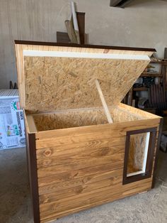 an open wooden box sitting on top of a floor next to a pile of wood