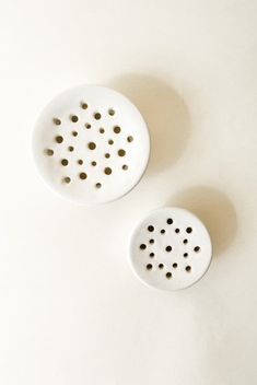 two white ceramic graters sitting on top of a table