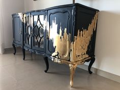 an ornate black and gold painted cabinet against a white wall