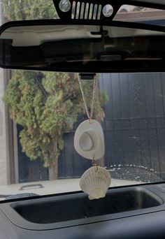 a white shell hanging from the windshield of a car