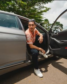 a man sitting in the open door of a car with his foot propped up against the door