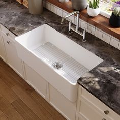 a white kitchen sink sitting on top of a counter next to a wooden window sill