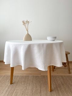 a table with a white cloth on it and a vase filled with flowers next to it