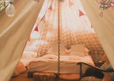 a bed in a tent with pillows and blankets on the floor next to a window