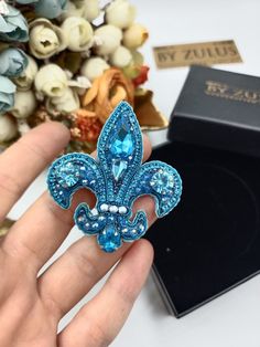 a blue brooch sitting on top of a table next to a box and flowers