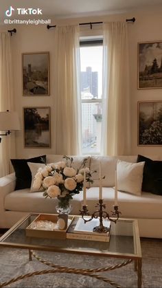 a living room filled with furniture and flowers on top of a coffee table in front of a window