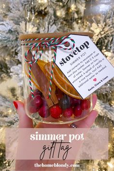 a person holding up a jar filled with candy and candies in front of a christmas tree