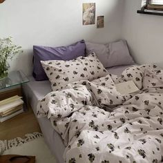 an unmade bed with white sheets and purple pillows