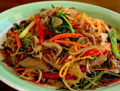 a green plate topped with meat and veggies on top of a wooden table