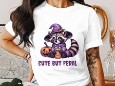 a raccoon wearing a witch hat and holding a pumpkin with the words cute but feria on it