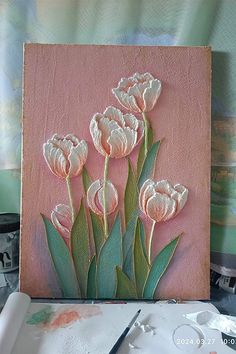 a painting with white flowers on it and some paintbrushes in front of it