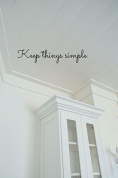 there is a white cabinet with writing on the wall above it that says, keep things simple