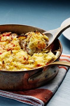 a casserole dish with meat and vegetables in it on a towel next to a fork