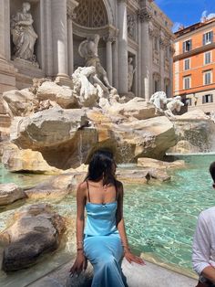 a woman sitting in front of a water fountain