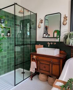 a green tiled bathroom with a sink, mirror and bathtub next to a tub