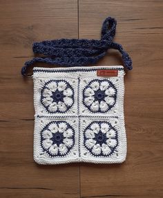 a crocheted bag with four squares on it sitting on a wooden floor next to a string