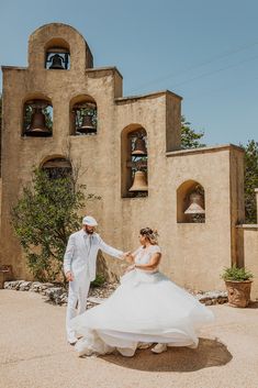 a bride and groom holding hands in front of an old building with bells on it