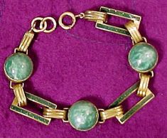 An Art Deco green glass and enamel bracelet circa 1920s. This lovely vintage period 7" length gilt brass link bracelet has Peking glass cabochons and fine emerald green baisse-taille enamel. It is most likely Czech / Czechoslovakian in manufacture.  There is a curling wave-like pattern visible in the emerald green enamel sections, and the Peking glass is also wavy without the usual spots. This beauty measures 1/2" across the light green stones, which are bezel set. It has a spring-ring catch, an Formal Green Enamel Jewelry, Art Deco Enamel Round Jewelry, Art Deco Round Enamel Jewelry, Art Deco Enamel Jewelry For Formal Occasions, Retro Green Enamel Jewelry, Green Cabochon Enamel Jewelry, Art Deco Jade Jewelry For Formal Occasions, Formal Art Deco Jade Jewelry, Green Cabochon Bracelet For Formal Occasions