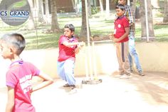 three young boys playing baseball in an enclosed area with trees and grass behind the fence