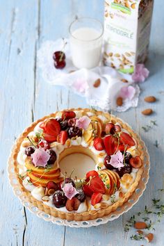 a cake with fruit and nuts is on a plate next to a carton of milk