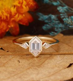 a diamond ring sitting on top of a wooden table next to some yellow and orange flowers