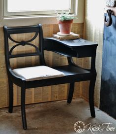 a black chair sitting next to a window with a potted plant on top of it