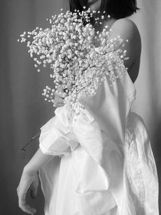 a woman wearing a white dress holding a bouquet of flowers