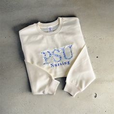 Introducing our personalized embroidered sweatshirt, the perfect choice for a thoughtful and unique gift for anyone on your list! Whether it's for a recent grad, a sports enthusiast, or a beloved family member, this customizable sweatshirt allows you to add a personal touch to the front with text of your choice. Product Features: Made from a cozy blend of 50% cotton and 50% polyester, ensuring comfort and durability. Classic crewneck design for a timeless look and feel. Available in a variety of Cream Cotton Sweatshirt With Embroidered Logo, Cream Cotton Sweatshirt With Letter Embroidery, Cream Cotton Sweater With Embroidered Logo, Cream Crew Neck Sweatshirt With Letter Embroidery, Cream Cotton Sweatshirt With Embroidered Text, White Fleece Sweatshirt With Embroidered Text, White Fleece Top With Custom Embroidery, Cream Sweatshirt With Embroidered Logo Relaxed Fit, Cream Embroidered Crew Neck Sweatshirt