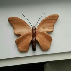 a wooden butterfly mounted to the side of a wall