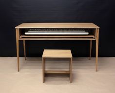 a computer desk with a keyboard on top of it next to a small stool and table