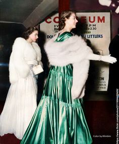 two women dressed in evening dresses and fur stolers talking to each other at an event