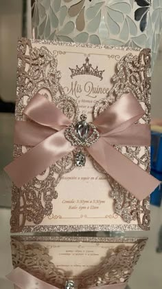 the wedding card is decorated with pink ribbon and a jeweled brooch on top