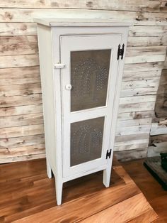 a white cabinet sitting on top of a wooden floor