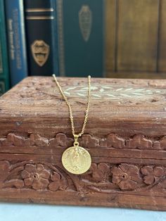 a small gold coin on a chain sitting on top of a wooden box next to some books