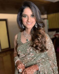 a woman in a green and gold sari with her hands on her hips, smiling