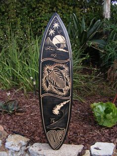 a surfboard sitting on top of a pile of rocks next to some grass and bushes