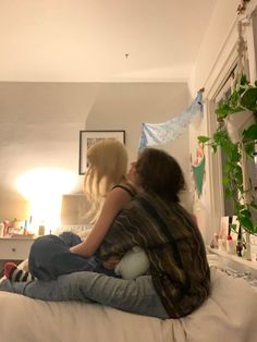 two people sitting on a bed in a room