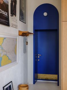 a blue door in a white room with pictures on the wall and posters above it