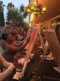 a group of people sitting around a table painting