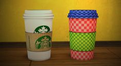 three different colored starbucks cups sitting next to each other on a wooden table in front of a yellow wall