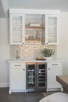 a kitchen with white cabinets and glass front refrigerator freezer doors are open to reveal an empty dishwasher