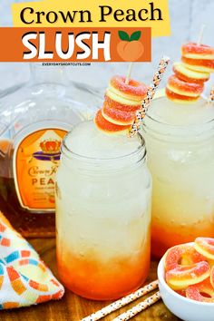 two mason jars filled with peach slush next to orange slices and strawberries on sticks